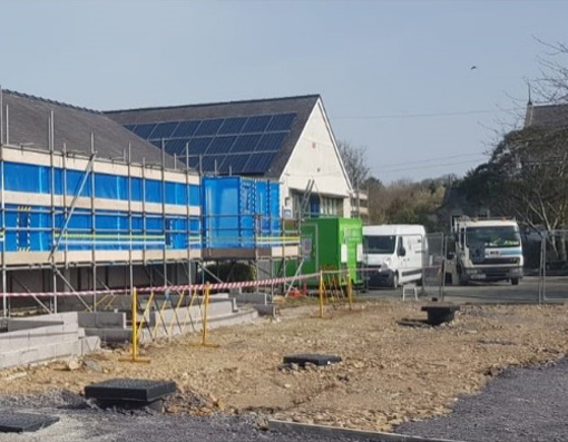 Asbestos removal enclosure set-up on elevated scaffold platform with Decontamination unit and waste van visible